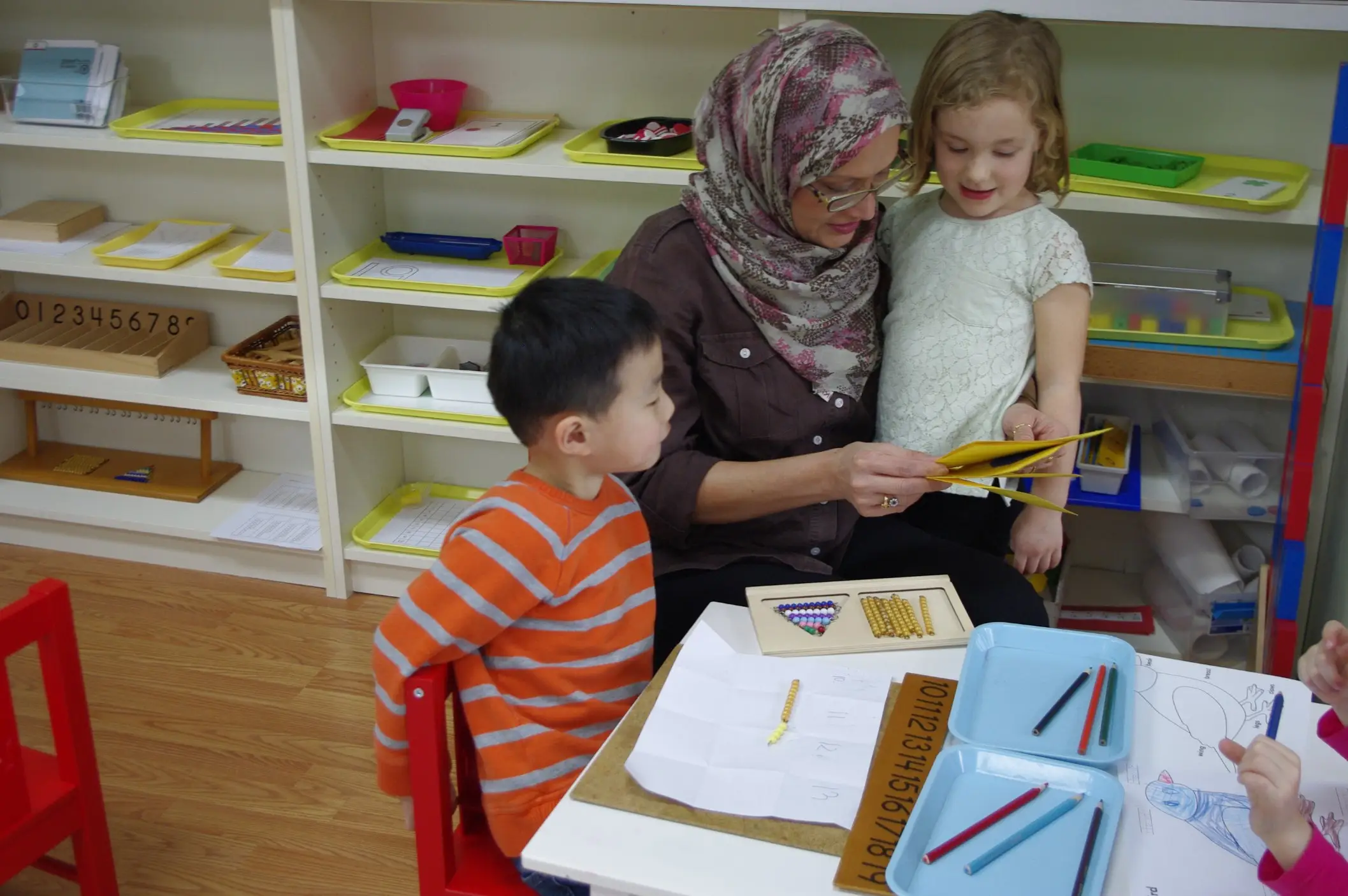 curious children with teacher learning in aster montessori school